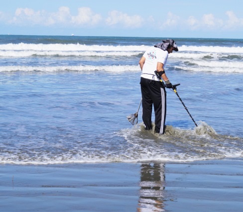 Detectorista pesquisando na água da praia do mar com o detector MX SPORT White